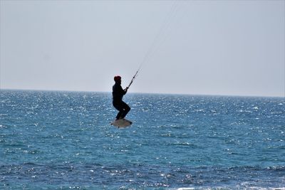 Man kiteboarding on sea against sky
