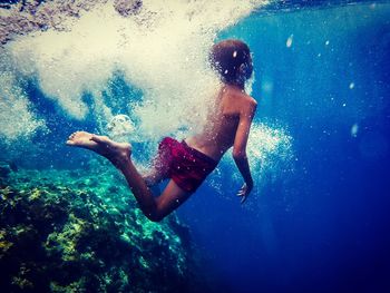 Full length of shirtless boy swimming in sea