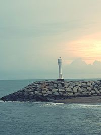 Lighthouse by sea against sky