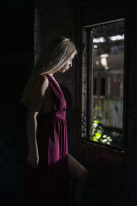 Woman standing by window at night