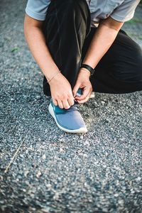 Low section of person tying shoes on field