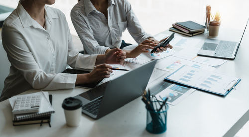 Midsection of business people working on table