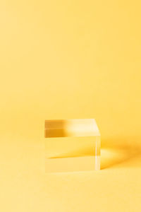 Close-up of yellow paper on table against orange background