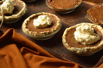 Homemade mini pumpkin pies with black sesame seed crust topped with whipped cream