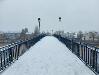 Snow covered street against sky during winter