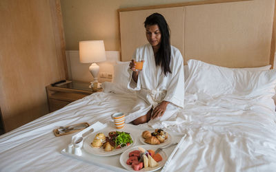 Portrait of young woman using mobile phone on bed at home