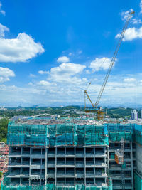 Construction site by buildings against blue sky