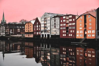 Buildings by river against sky