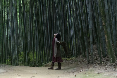 Rear view of woman standing in bamboo forest