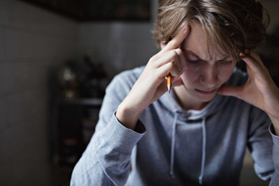 Stressed teenage boy with head in hands studying at home