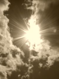 Low angle view of sunlight streaming through clouds