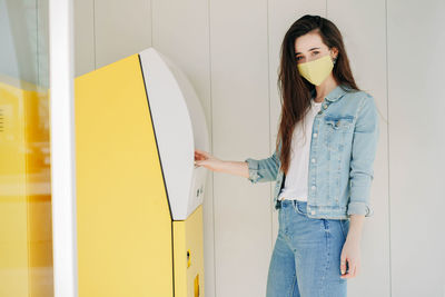 Portrait of young woman standing against wall