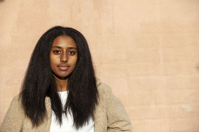 Portrait of teenage girl standing against wall