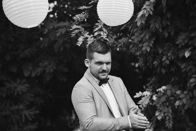 Portrait of young man standing against plants