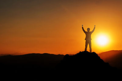 Double exposure of man standing on silhouette mountain against sky during sunset