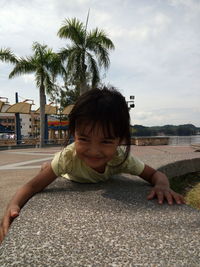 Portrait of cute boy smiling on sand against sky