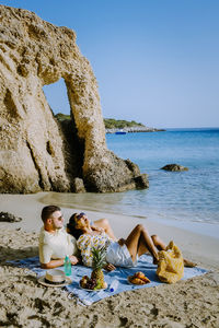 Woman sitting on beach against clear sky