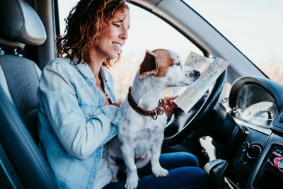 Woman with puppy analyzing map in camper trailer