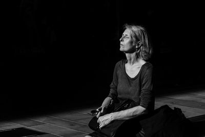 Woman looking away while sitting on floor