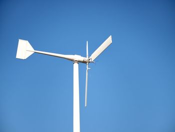 Low angle view of wind turbine against clear blue sky