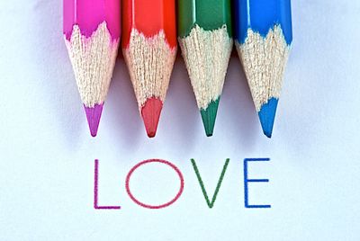 Close-up of love text with colored pencils on white background