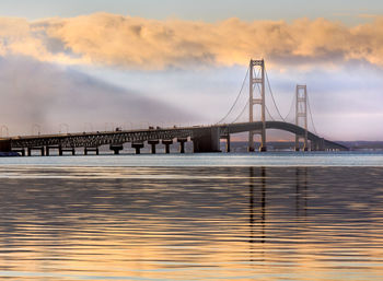 Bridge over river against cloudy sky