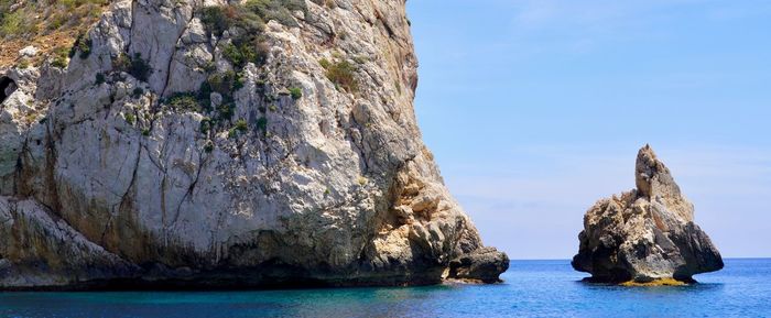 Rock formation in sea against blue sky