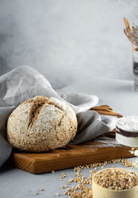 Homemade loaf of freshly baked green buckwheat bread lies on a wooden board. gray linen napkin