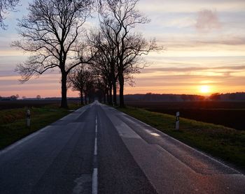 Road amidst trees against sky during sunset