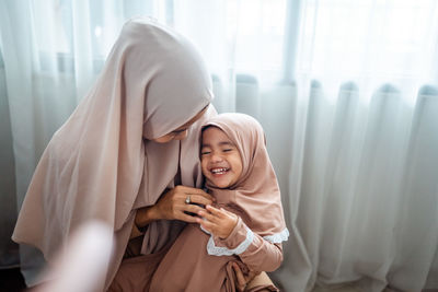 Mother tickling daughter at home