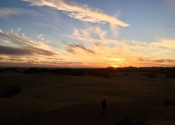 Silhouette people on field against sky during sunset