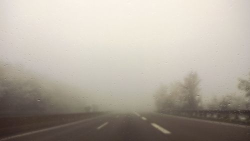 Road seen through wet window in rainy season