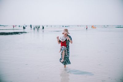 Mother playing with son in sea against sky