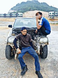 Portrait of young men sitting on car