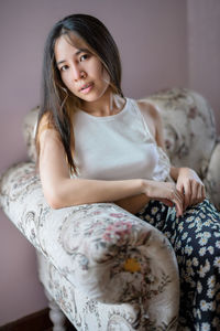 Portrait of young woman sitting on bed at home