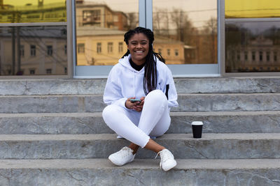 Full length of woman sitting on steps outdoors