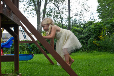 Full length of girl on ladder in playground against trees