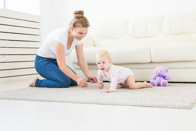 Happy mother and daughter sitting on floor at home