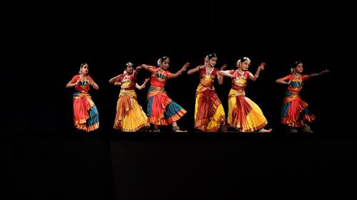 Group of people dancing against black background