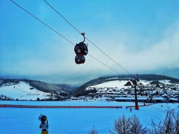 Overhead cable car over snowcapped mountains against sky