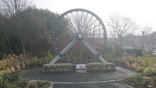 Ferris wheel by bare trees against clear sky