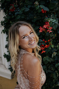 Portrait of smiling young woman standing against plants