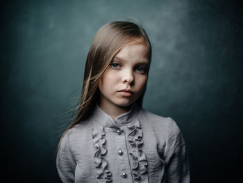 Portrait of cute girl standing against gray background