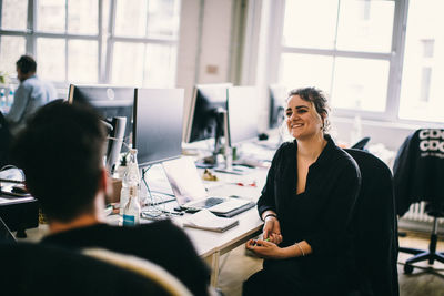 Smiling business colleagues discussing while sitting at office