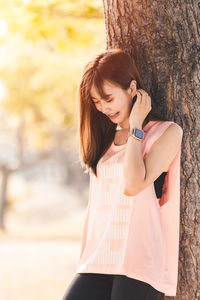 Young woman standing on tree trunk