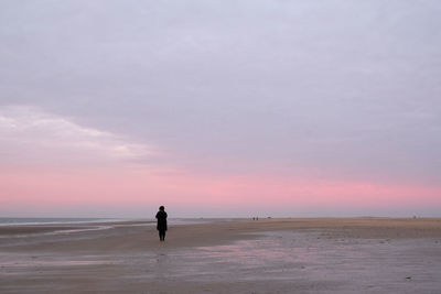 Distant woman at beach during sunset