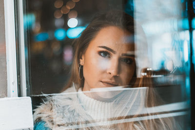 Portrait of young woman looking through window