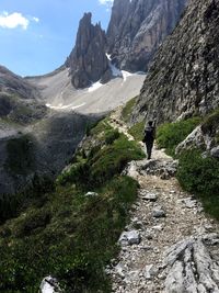 Man standing on rock by mountain against sky
