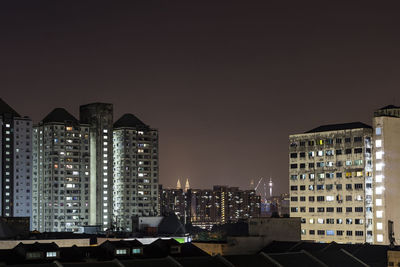 Illuminated buildings in city against clear sky at night