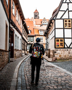 Rear view of man walking on street amidst building